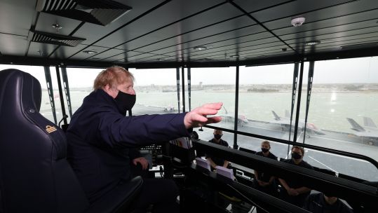 PM Boris Johnson looks up from his seat at the controls of HMS Queen Elizabeth