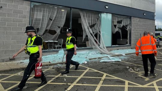 People clear debris at the Holiday Inn Express in Rotherham, South Yorkshire, where anti-immigration rioters smashed the windows before starting fires on Sunday 050824 CREDIT PA.jpg