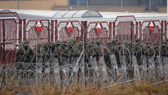 Polish security forces stand behind the border fence at the Brusgi (Belarus) and Kuznica (Poland) border crossing