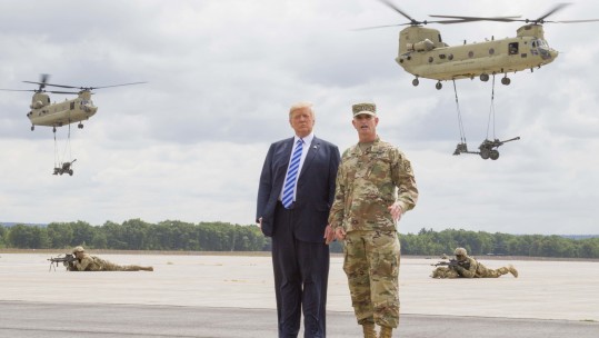 President Donald J. Trump and Maj. Gen. Walter E. Piatt, commander of the 10th Mountain Division (LI), look on as CH-47 Chinook helicopters carry in artillery during a demonstration at Fort Drum, New York, Aug 13 CREDIT DVIDS
