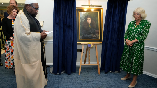 Queen Camilla listens to Squadron Leader Imam Ali Omar read a blessing at the RAF Club in London where she unveiled a portrait of SOE Operative, Noor-un-Nisa Inayat Khan (Picture: PA MEDIA)
