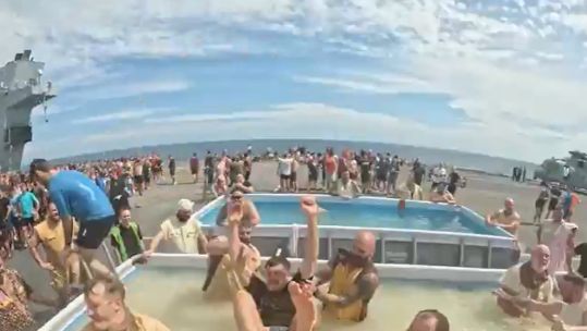 Personnel on board the flagship pay their respects to King Neptune