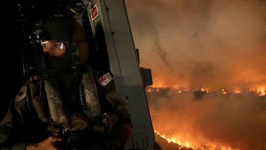 Cover Image: A Royal Australian Navy aircrewman over the wildfires in New South Wales (Picture: Australian Defence Force).