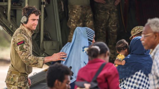 Royal Marine assists evacuees on to the RAF C-130 at Wadi Seidna airport in Sudan