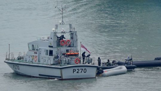 A Royal Navy vessel tows boats, thought to have been used by migrants, into Dover, Kent 