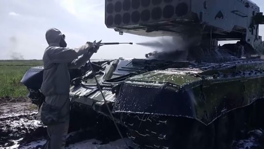 Russian personnel washing down a tank with protective suit in case of chemical exposure (Picture: Russian MOD).