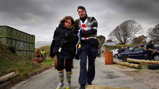 HMS Kent sailor with civilian at disaster relief exercise