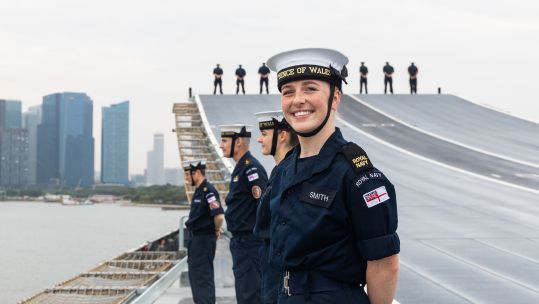 Sailors line up on the flightdeck of HMS Prince of Wales as she arrives in Singapore