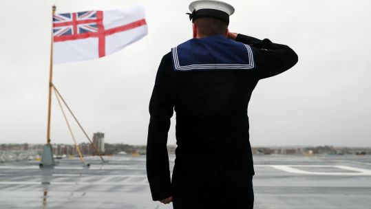 Semi anonymous Royal Navy sailor salutes White Ensign on HMS Prince of Wales