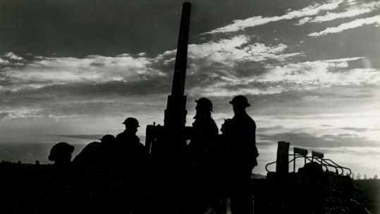 Silhouettes of soldiers around an anti-aircraft gun on the Western Front in World War Two