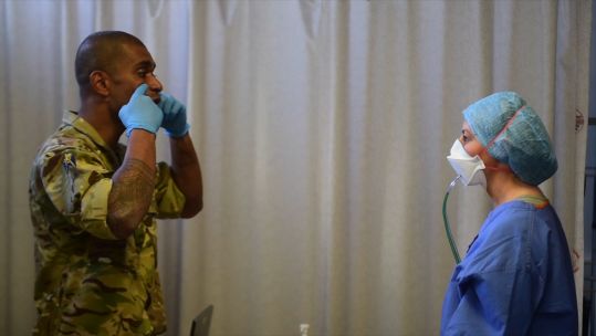 Soldier shows NHS nurse how to ensure mask fits well 