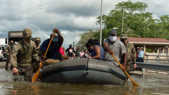 Cover image: Soldiers from The Royal Dragoon Guards help locals into an inflatable boat so they can cross a flooded road (Picture: MOD).