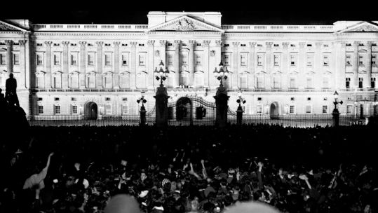 The floodlit Buckingham Palace with the crowd cheering King George VI and Queen Elizabeth after his speech on VJ Day
