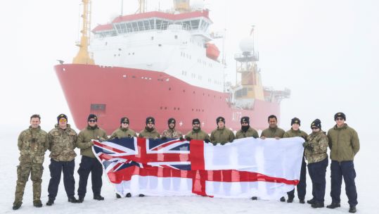 The survey and research team in front of HMS Protector on her record breaking Arctic expedition (Picture: Royal Navy).