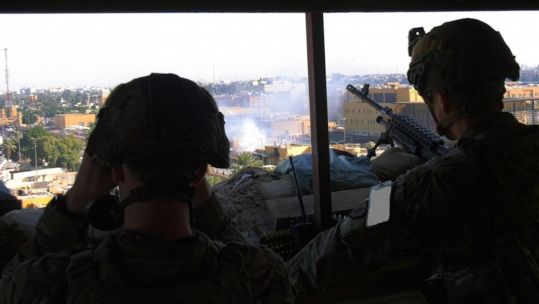 US troops watch crowds protesting outside a section of the US Embassy in Baghdad (Picture: US Department of Defense).