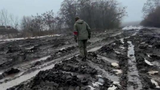 Ukrainian personnel walking through vehicle tracks