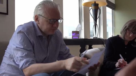 Julian Assange discusses the text if his plea deal on a sheet of paper following his release from Belmarsh (Picture: Reuters).