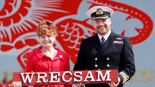 Wrexham MP Sarah Atherton and HMS Dragon's Commanding Officer, Commader Iain Giffin, with the name of the city using the Welsh spelling (Picture: MOD)