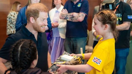 A bereaved child presents Prince Harry with a Scotty's Little Soldiers hoodie on 9 May 2024 CREDIT Scotty’s Little Soldiers