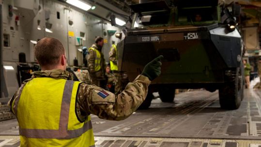 A Royal Air Force serviceman directs the loading of a French armoured vehicle onto a C-17 at Evreux, France, as the UK assists France to move military equipment to Mali, West Africa.