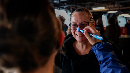 A member of the crew onboard HMS Queen Elizabeth having her nose painted blue (Picture: Royal Navy).