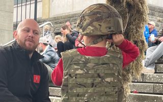 A would-be infanteer tries on a helmet and plate carrier as the returning soldiers showed off their kit