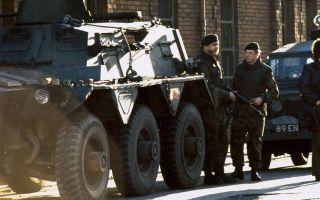 Soldiers supported by a Saracen armoured personnel carrier patrol a Catholic area of Belfast in 1973 - over half a century later the Troubles Bill may soon become law (Picture: Alamy)