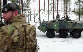 A soldier from 3 Rifles scans the ground ahead as a Finnish Patria Pasi APC passes by
