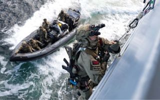 Royal Marine from K Company, Royal Navy, uses a caving ladder to gain entry onto a vessel (Picture: MOD)