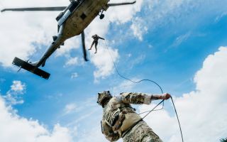 A US Navy explosive ordnance disposal technician secures a rope on the ground for a Peruvian navy counterpart descending from an SH-60 Sea Hawkat Bellows Air Force Station in Hawaii (Picture: US Department of War)
