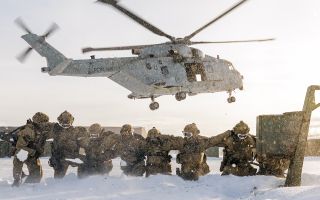  Members of 42 Commando protect themselves from the downwash and whipped up snow after fast-roping from an 845 Naval Air Squadron Merlin Mk4 in Norway