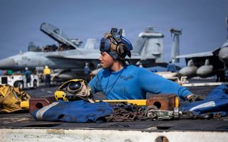 US Navy Aviation Boatswain's Mate Zyrus Rabosa operates a tractor on the flight deck of the USS Abraham Lincoln in the Arabian Sea