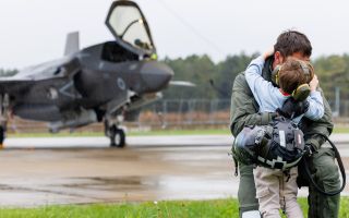 An F-35B pilot from 617 Squadron gives his son a hug in the rain after flying back to RAF Marham at the end of Operation Highmast