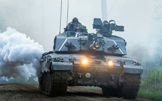 This Challenger 2 is producing concealing smoke as it takes part in Exercise Spring Storm in Estonia - the tanks are being recalled to the UK where many will be upgraded to Challenger 3 specification (Picture: MOD)