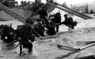 Personnel from No. 48 (Royal Marine) Commando wade through the surf and debris as they come ashore during D-Day (Picture: Royal Navy)