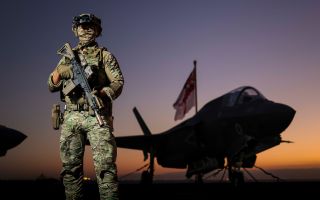 A Royal Marines Commando armed with a Sig Sauer MCX rifle stands guard on the flight deck of HMS Prince of Wales as she transits the Suez Canal