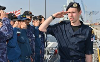 A member of the Royal Navy salutes the JMSDF as he walks down a line of JMSDF personnel (Picture: JMSDF X)