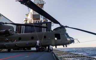 A Chinook helicopter – here ZH777 – just about fits on the aircraft lift, its nose protruding over the edge (Picture: MOD)