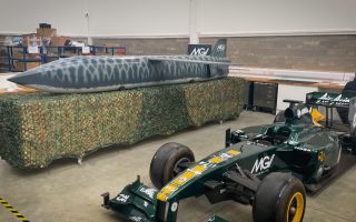 One of MGI Engineering's drones sits next for a Formula One car