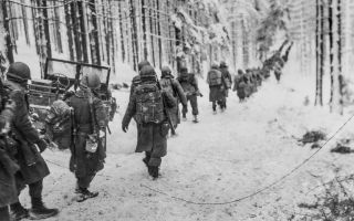 Image ID 2J2EW77 US infantry soldiers march along the snow-covered road on their way to cut off the Saint Vith-Houffalize road in Belgium during the Battle of The Bulge NO REUSE CREDIT Shawshots / Alamy Stock Photo