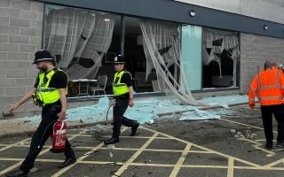 People clear debris at the Holiday Inn Express in Rotherham, South Yorkshire, where anti-immigration rioters smashed the windows before starting fires on Sunday 050824 CREDIT PA.jpg