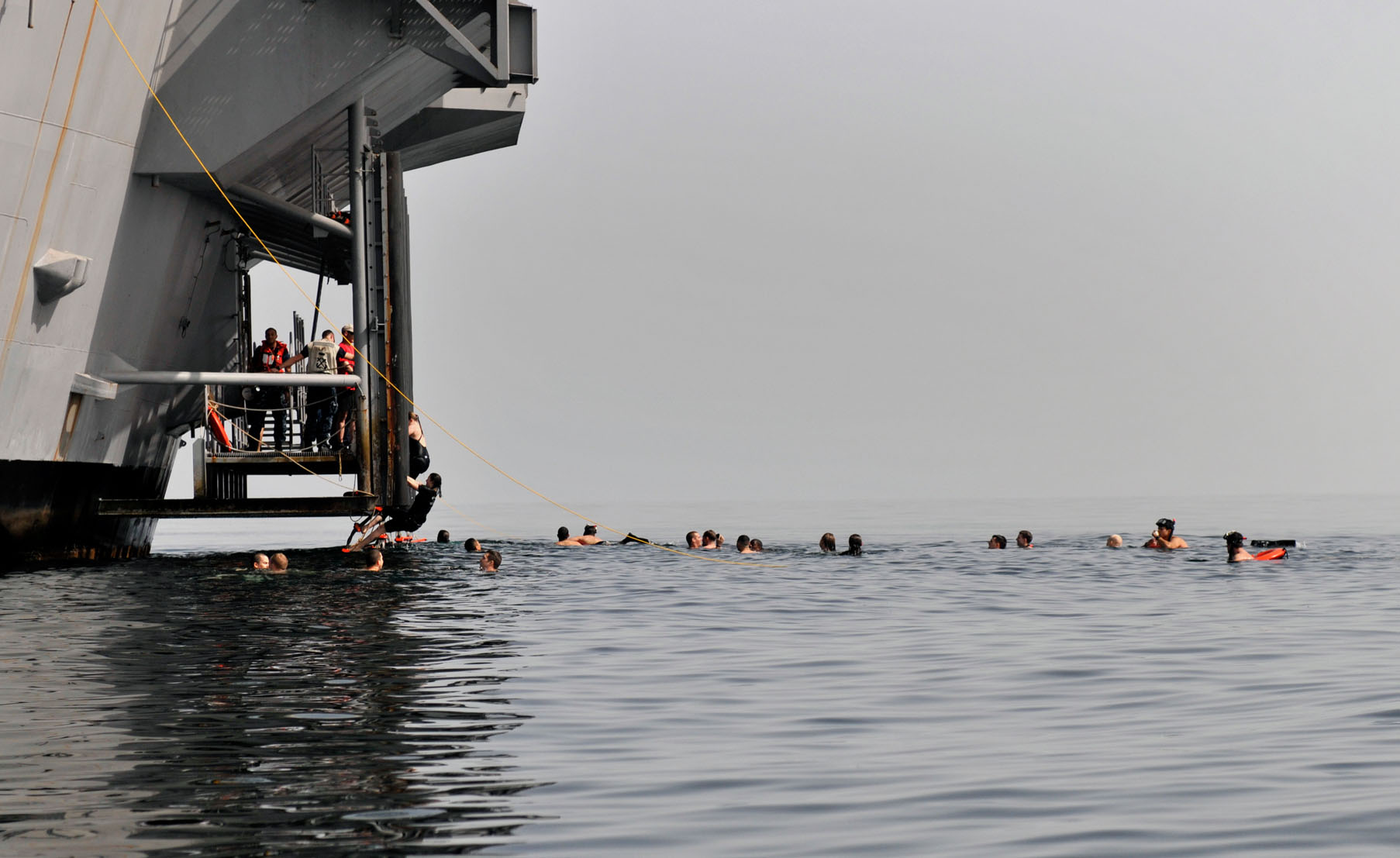 Sailors aboard aircraft carrier USS Carl Vinson swim after jumping off aircraft elevator No. 4 during a swim call. Picture: Z2A Collection / Alamy.