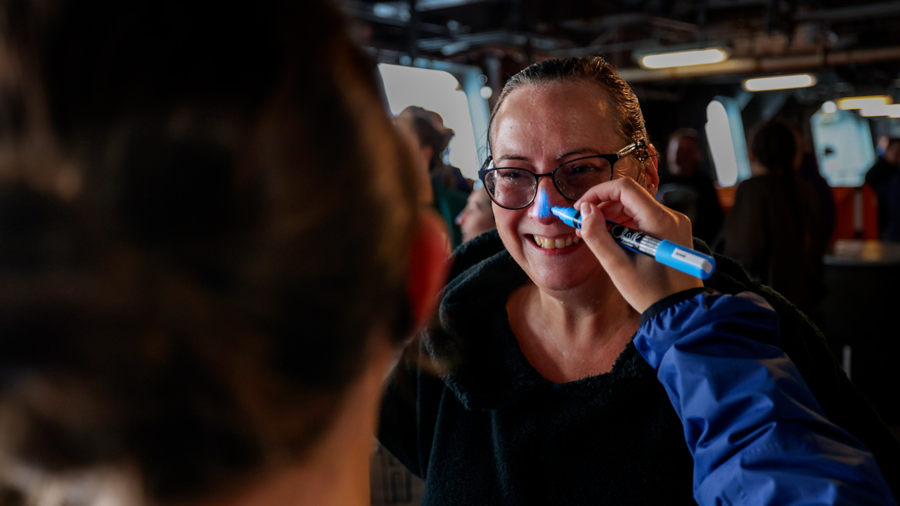 A member of the crew onboard HMS Queen Elizabeth having her nose painted blue (Picture: Royal Navy).